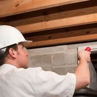 Termite inspection technician checking a basement wall and framing for termite activity in Honolulu, HI